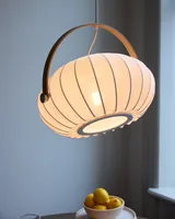 DC Textile Pendel Satinhvid fra Halo Design over et bord i en stue - blødt, varmt lys i hjemmet