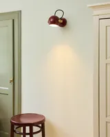 DC Væglampe Merlotrød og olieret eg fra Halo Design på en stol i en entré DC Væglampe Merlotrød og olieret eg fra Halo Design på en stol i en entré